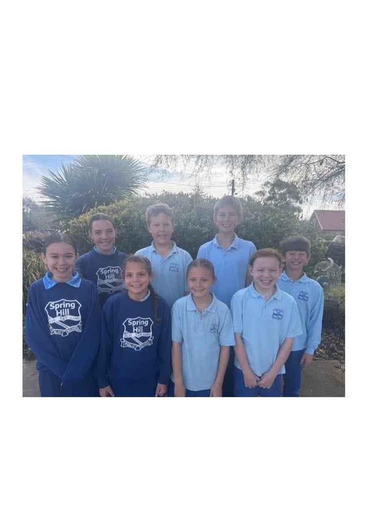 A group of eight students, a mix of boys and girls standing smiling at the camera in a posed photo.