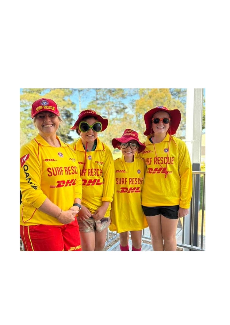 Four people wearing surf life saving uniforms. They all have red hats on, the yellow surf life saving shirts and the instructor also has red shorts on. The other 3 people in the image are students dressed up. The students also have goofy sunglasses on.