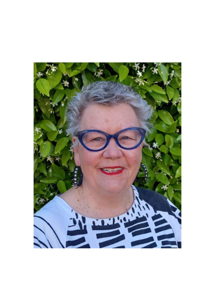 A photo of Spring Hill Public School APC&I, Sally Beer. Sally is a middle aged woman with short grey hair and wearing blue glasses with a black and white patterned shirt on. She also has large black and white hooped earrings.